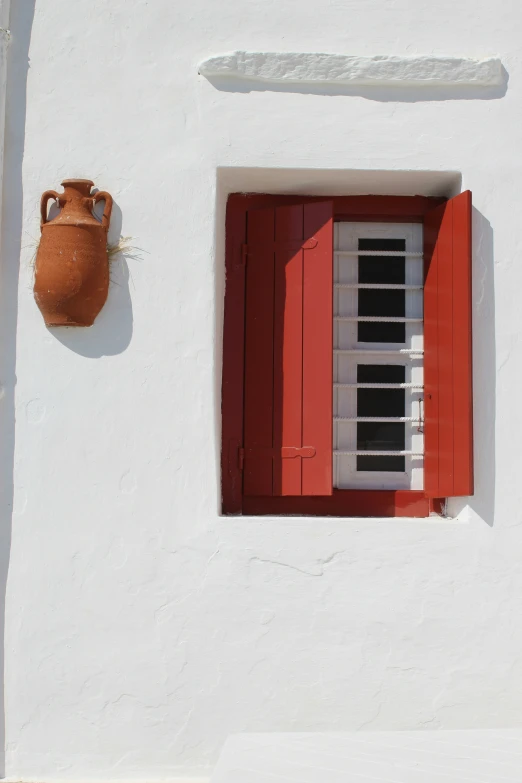 a white stucco house with red shutters and a window