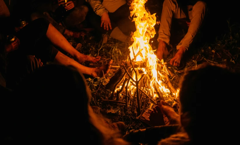 many people around a fire pit with burning wood