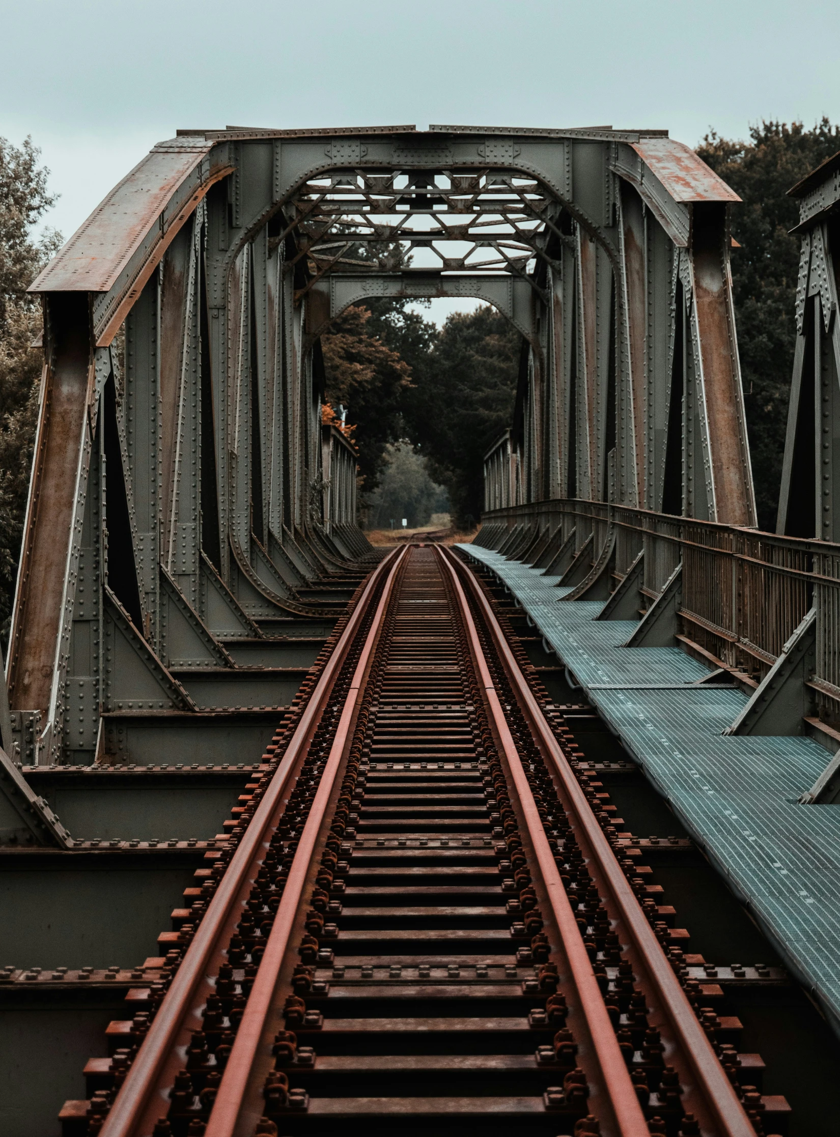 a train track with train tracks crossing under an old bridge