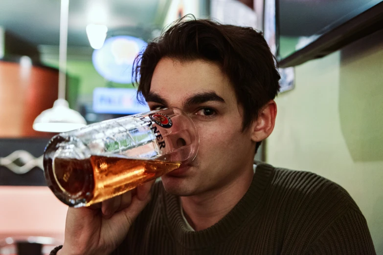 a young man drinking a glass of beer