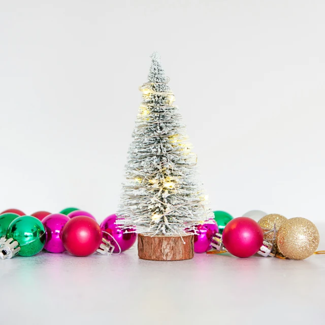 a small white christmas tree surrounded by christmas ornaments