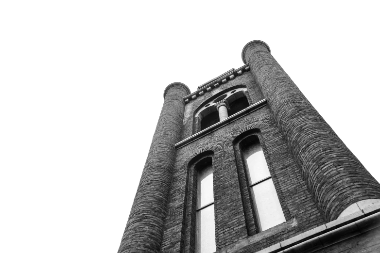 a tall brick building is silhouetted against a white sky