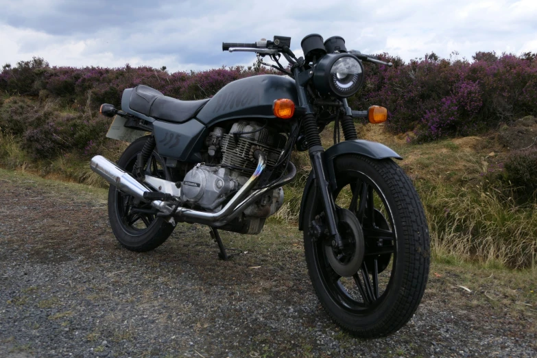 an old black motorcycle parked on the side of the road