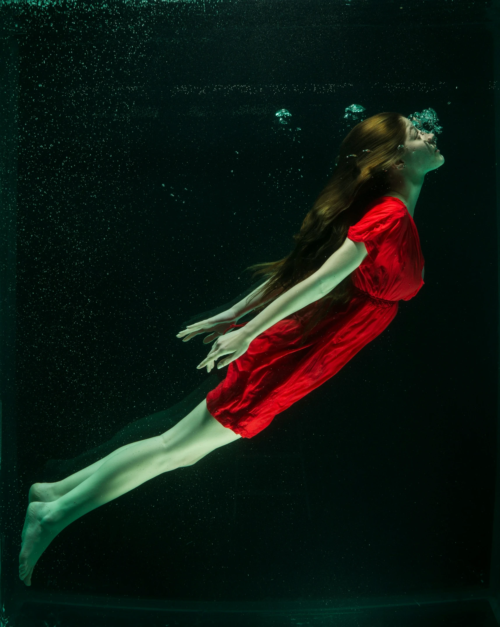 a woman is floating under water near glass