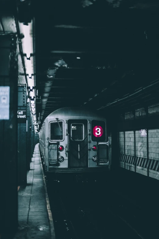 a subway train with red sign in front of it at a station