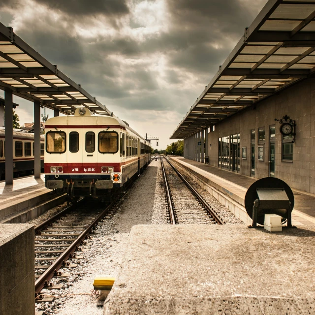 an abandoned train station with cloudy skies and a train