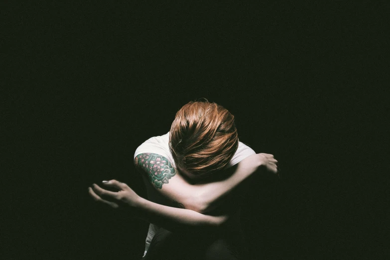 woman with tattoos on her arm sitting in the dark