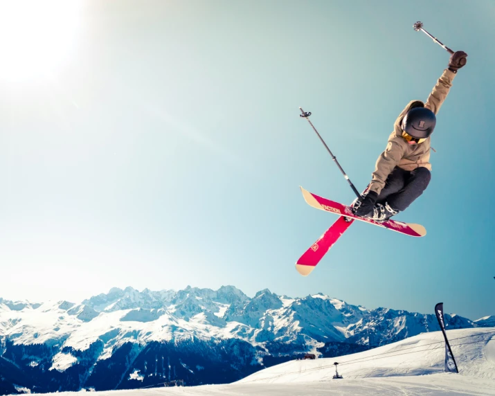 person in brown jacket jumping over a mountain