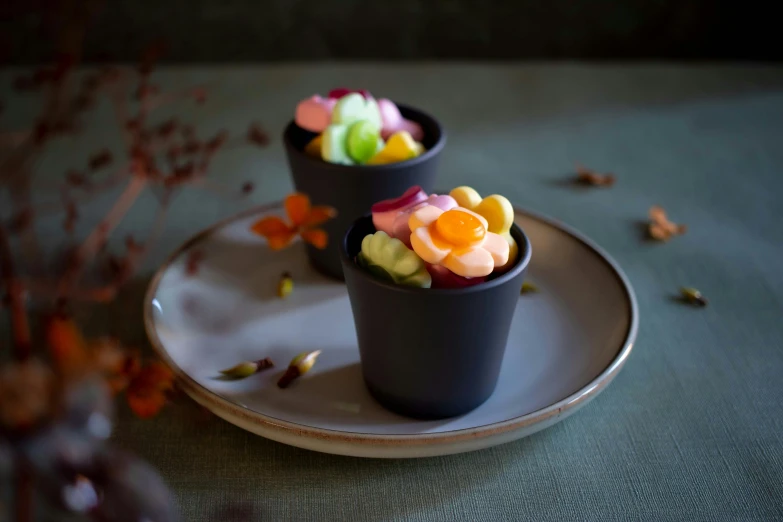 some small cups filled with colorful flowers on a white plate