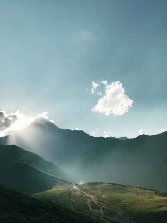 the sun shines through clouds over a mountain range