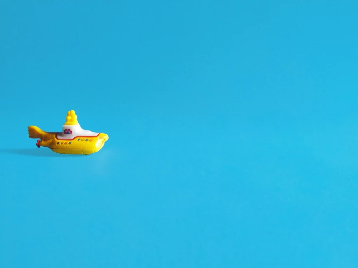 a toy yellow submarine floating on a blue water