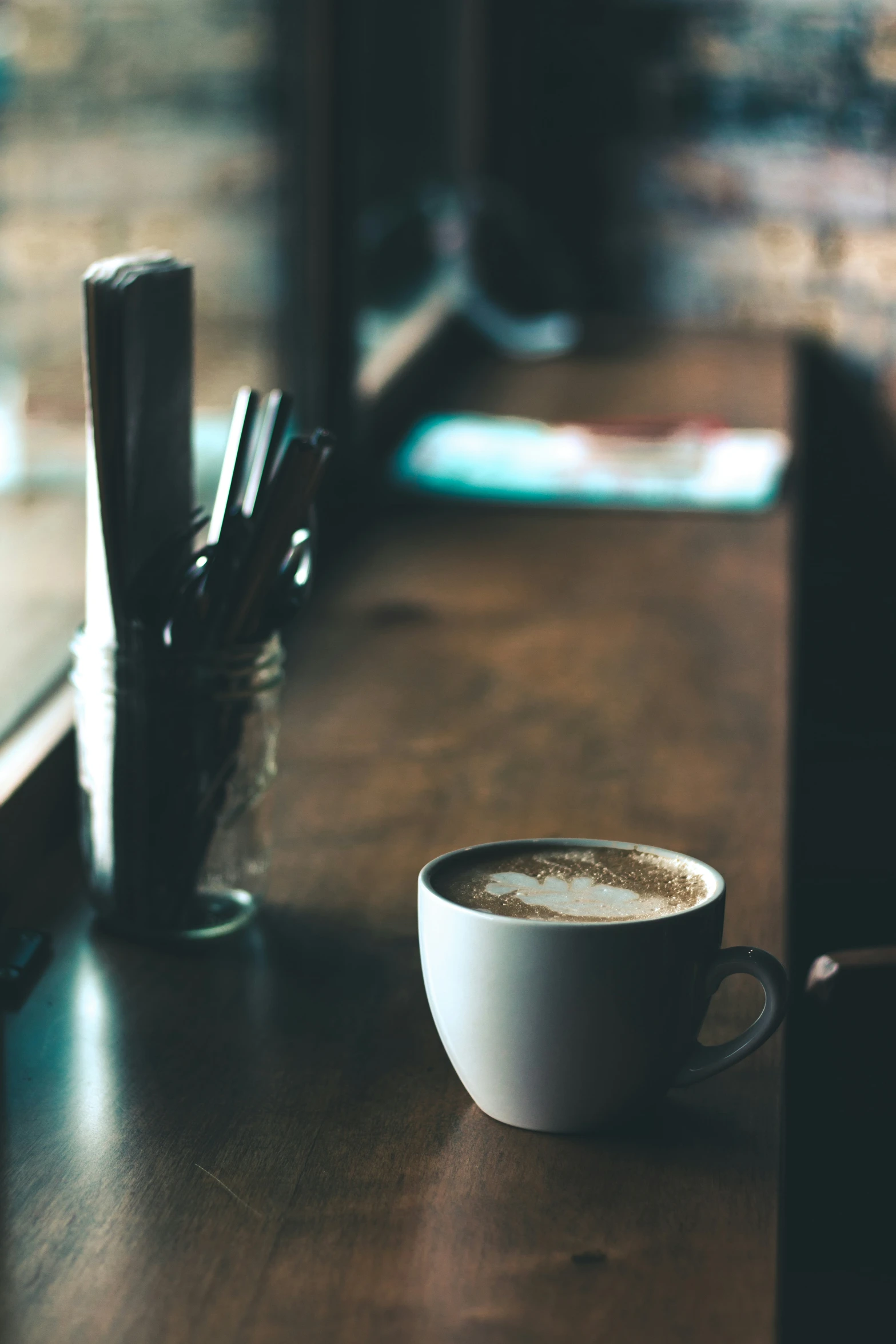 a cup filled with liquid sits on a table near pens