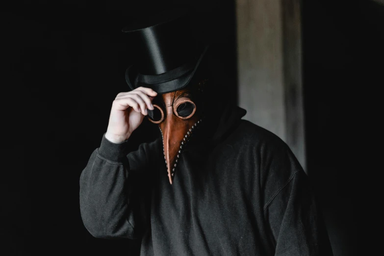 man with black hat and mask, wearing a long necked shirt and brown cowboy boots