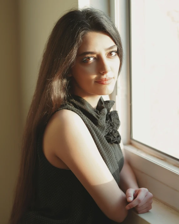 a woman in a black dress standing near a window