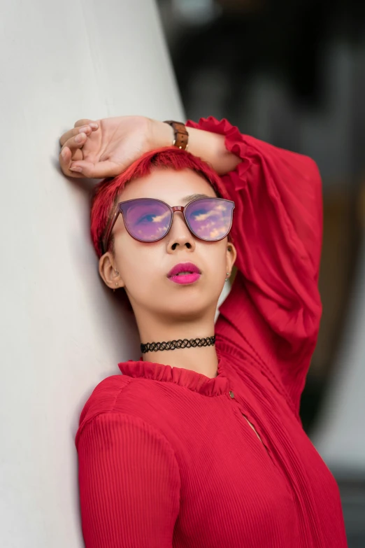 a woman with red hair wearing some pink shades and piercings