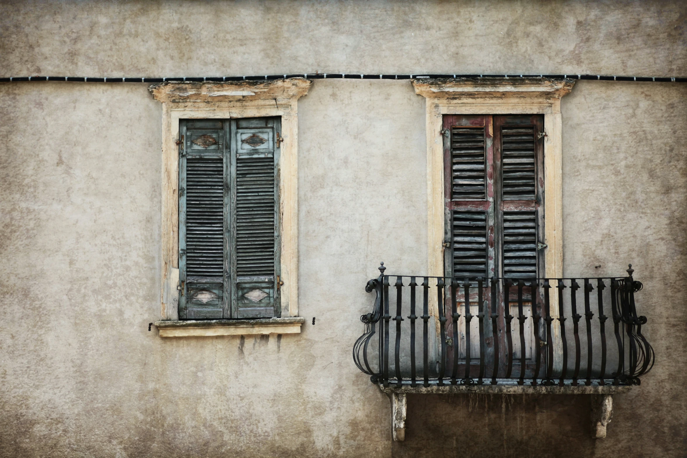 the corner of a building with an iron railing and two windows