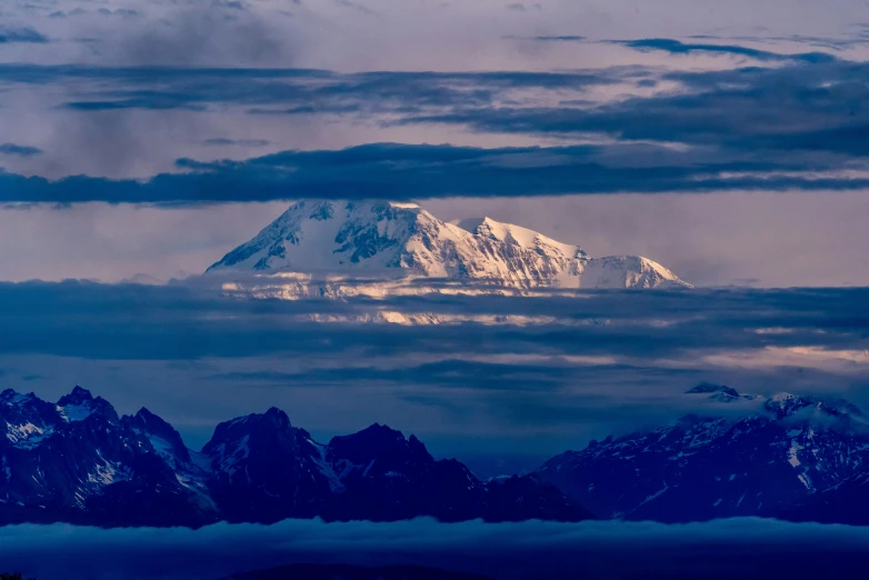 a snowy mountain range covered in clouds and mountains