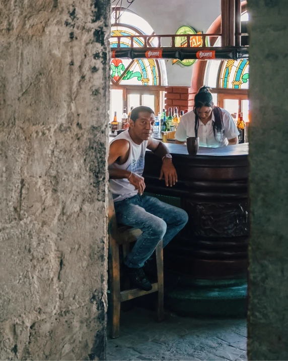 two men sitting at a bar with a lot of stained glass