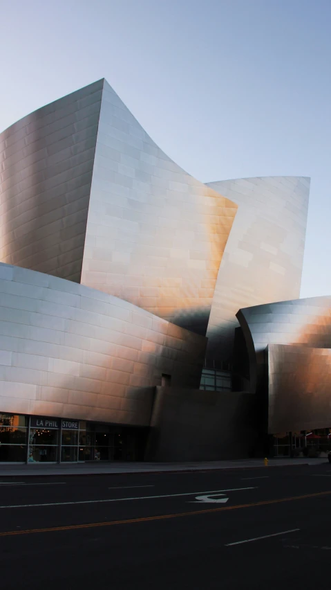 a car drives by a museum with the large metal building in the background