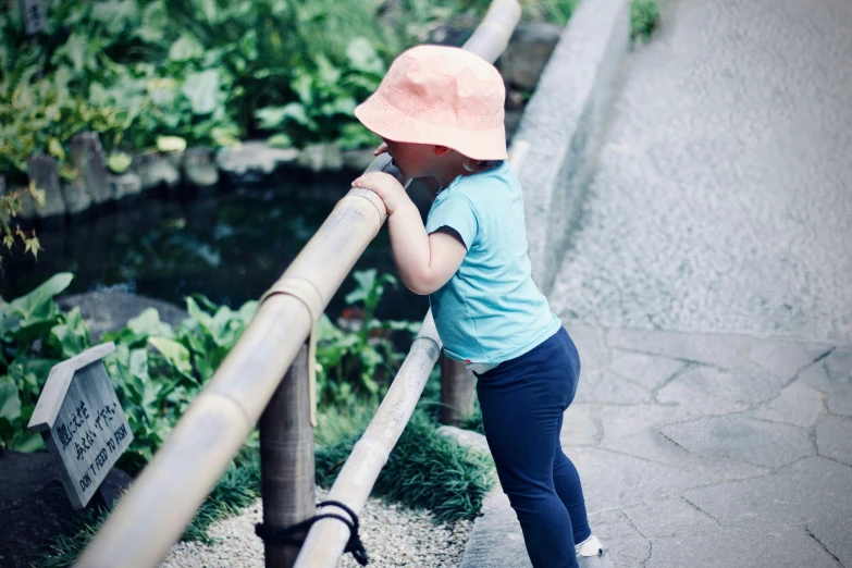 a little girl is leaning over the fence to look at soing