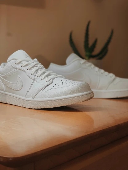white sneakers sitting on top of a wooden table