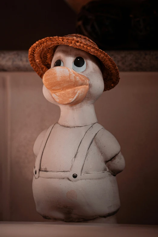 a snowman with an orange hat and overalls, posed as a toy