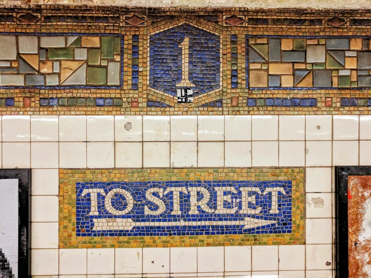 some tile signage near a building that says to street