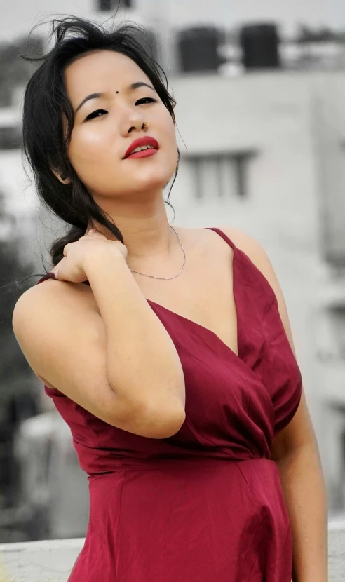 an oriental woman with dark hair and tattoos leaning against a wall