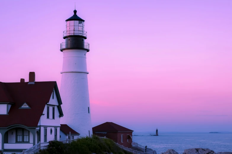 a house near a light house on a hill at sunset