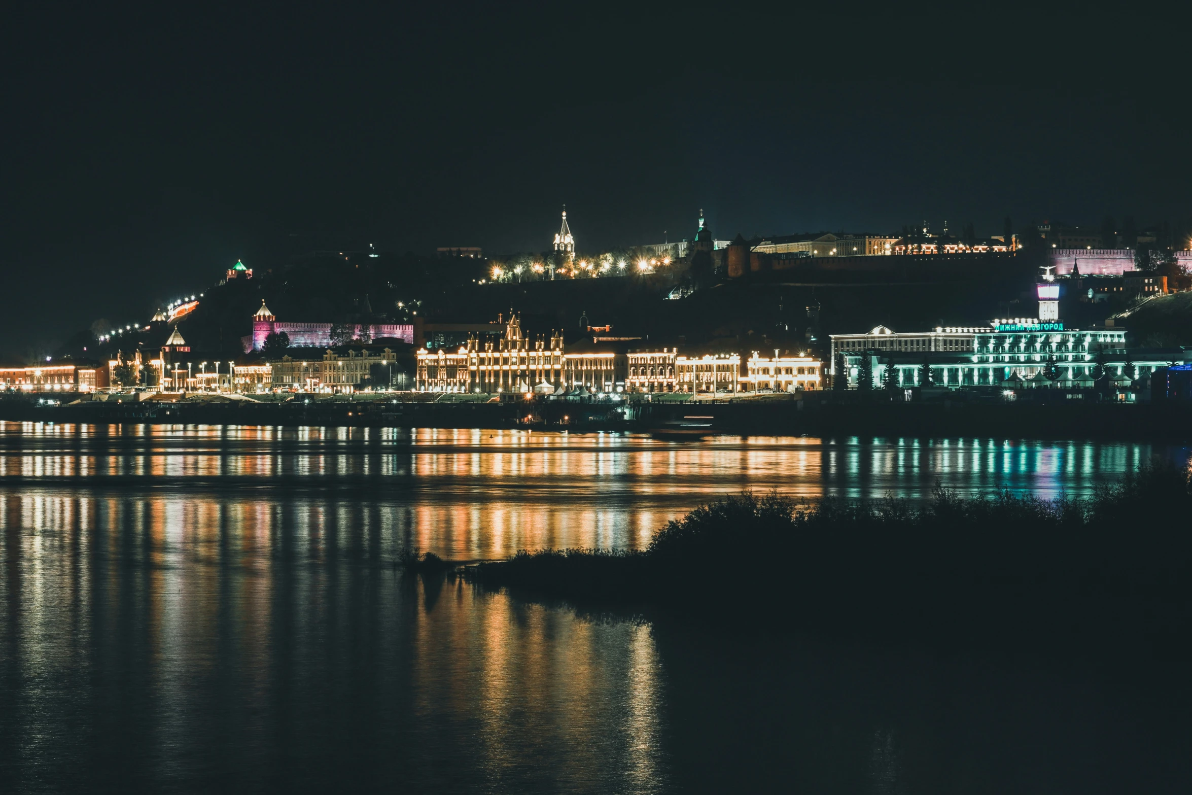 night scene of a waterfront town on a hilltop