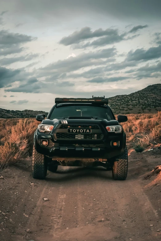 an suv is sitting in the dirt on a cloudy day