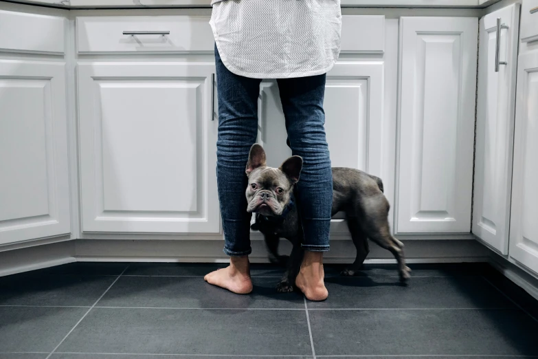 a woman standing in a kitchen next to her dog