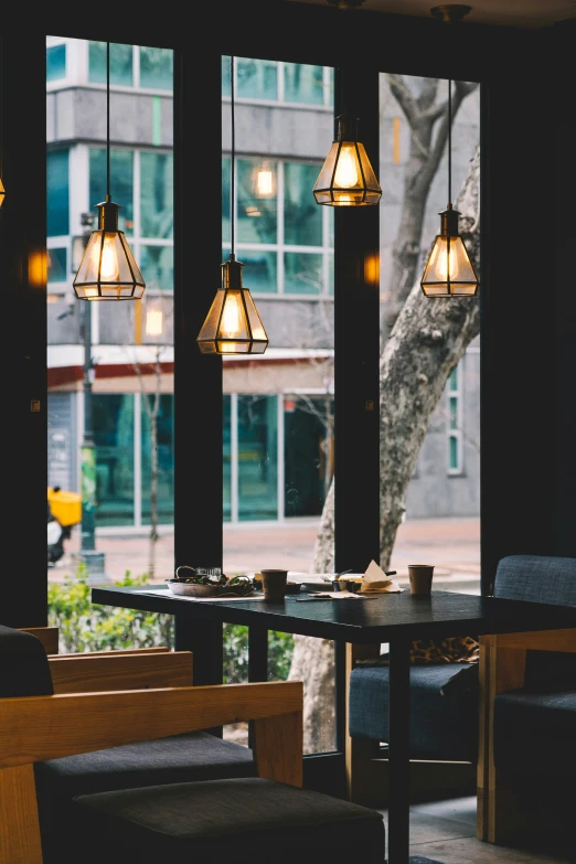 three hanging lamps that are hanging above tables