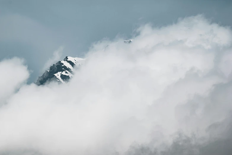 a plane flying over a mountain in the clouds
