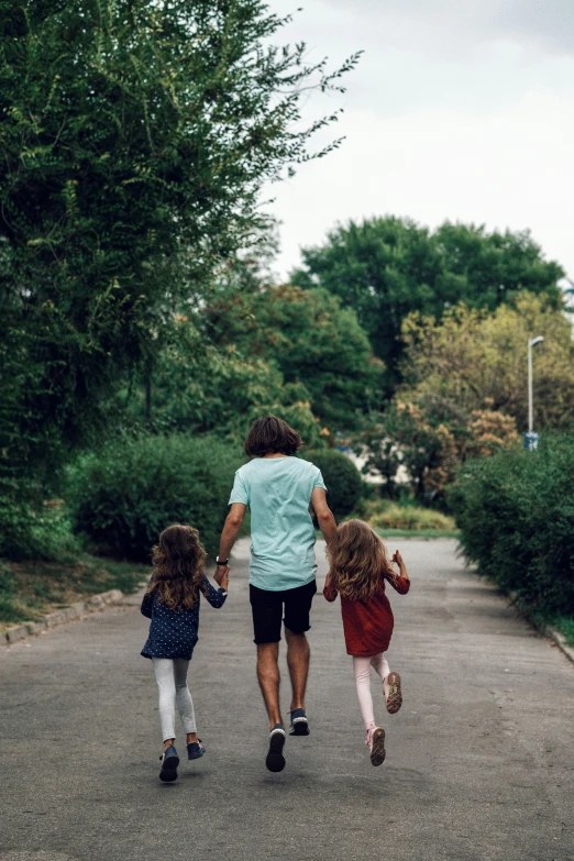 a man walking down a road with two children