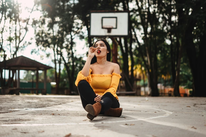 the woman in a yellow top sits on the basketball court