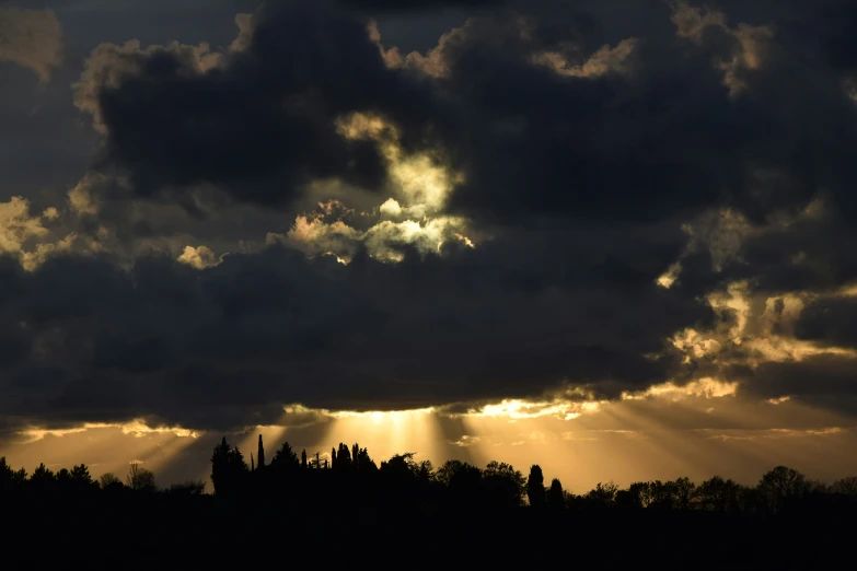 a cloudy sunset shines through the clouds