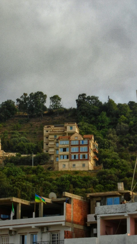 a view of an apartment building sitting on top of a green hillside