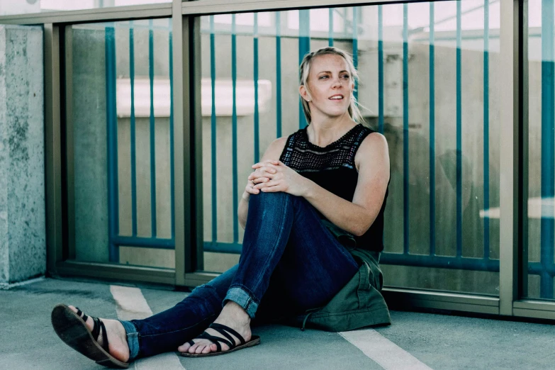 a young blonde woman sits alone in a parking lot