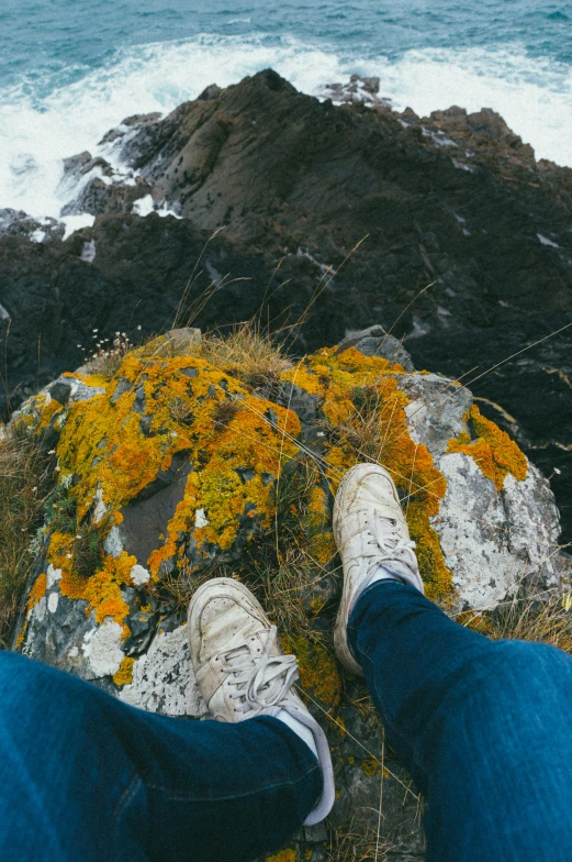 the legs and feet of two people overlooking water