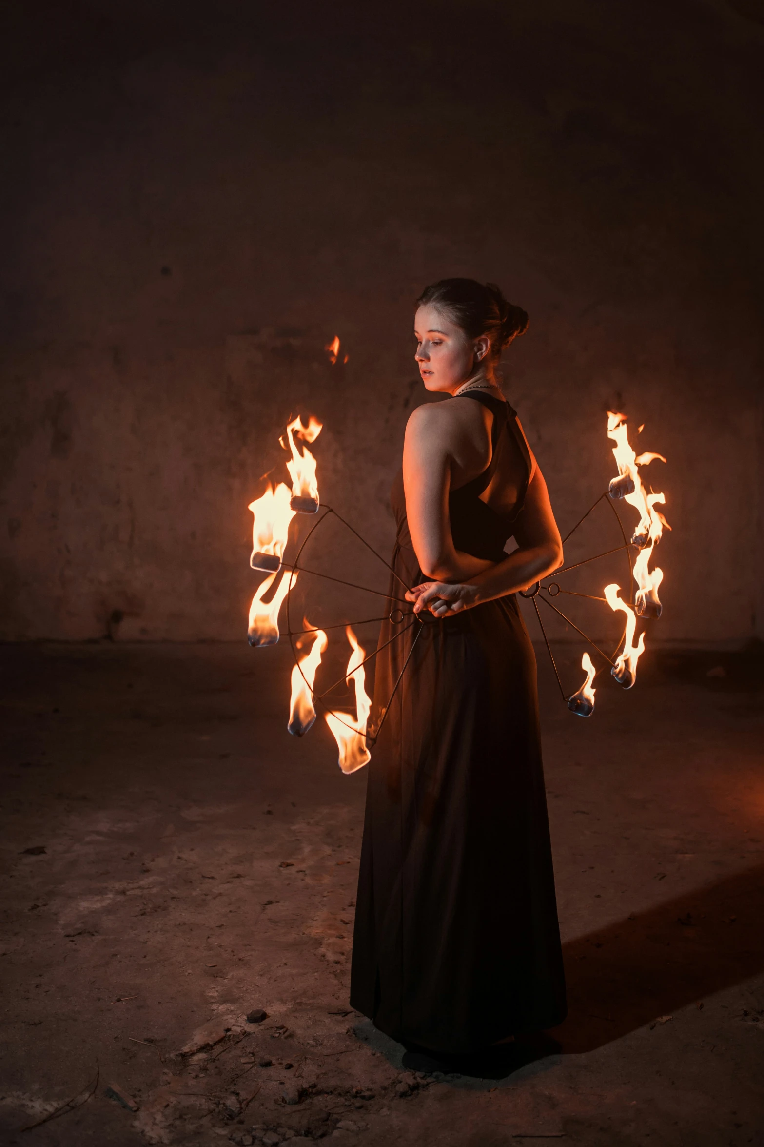 a woman is standing in the dark holding fire