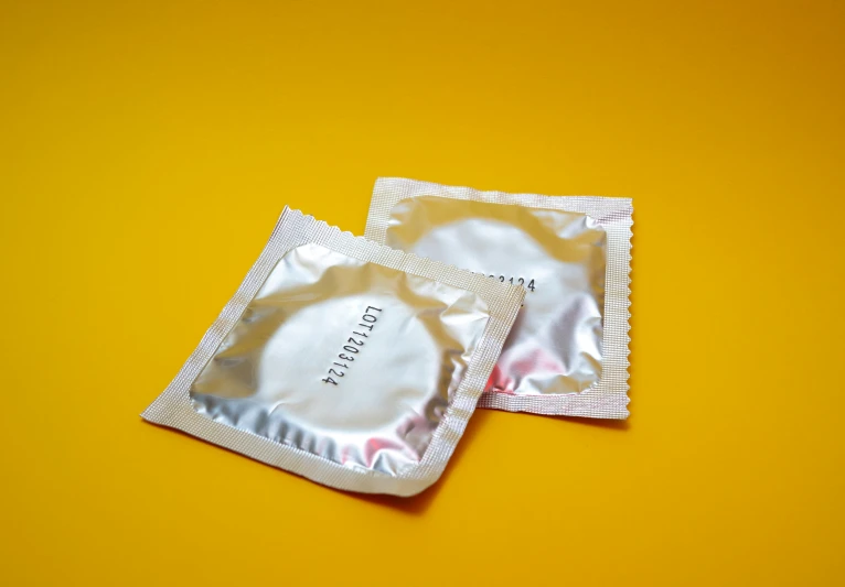 a pack of condoms laying on top of a yellow background