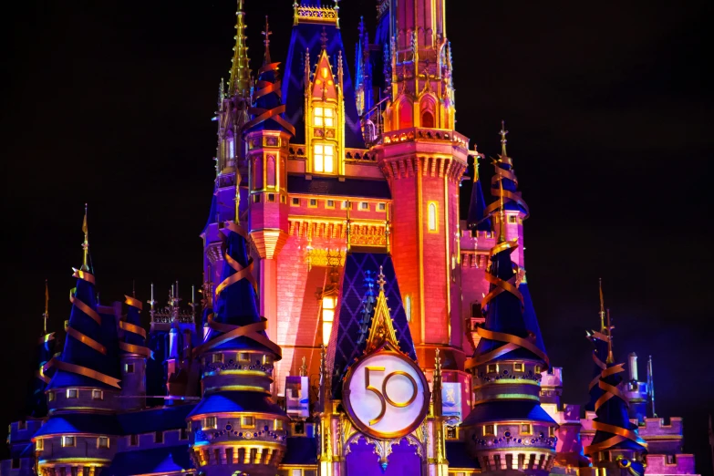 disneyland castle illuminated with colorful lights in the dark