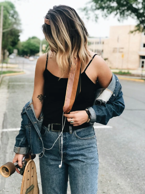 a girl is holding a skateboard while wearing headphones