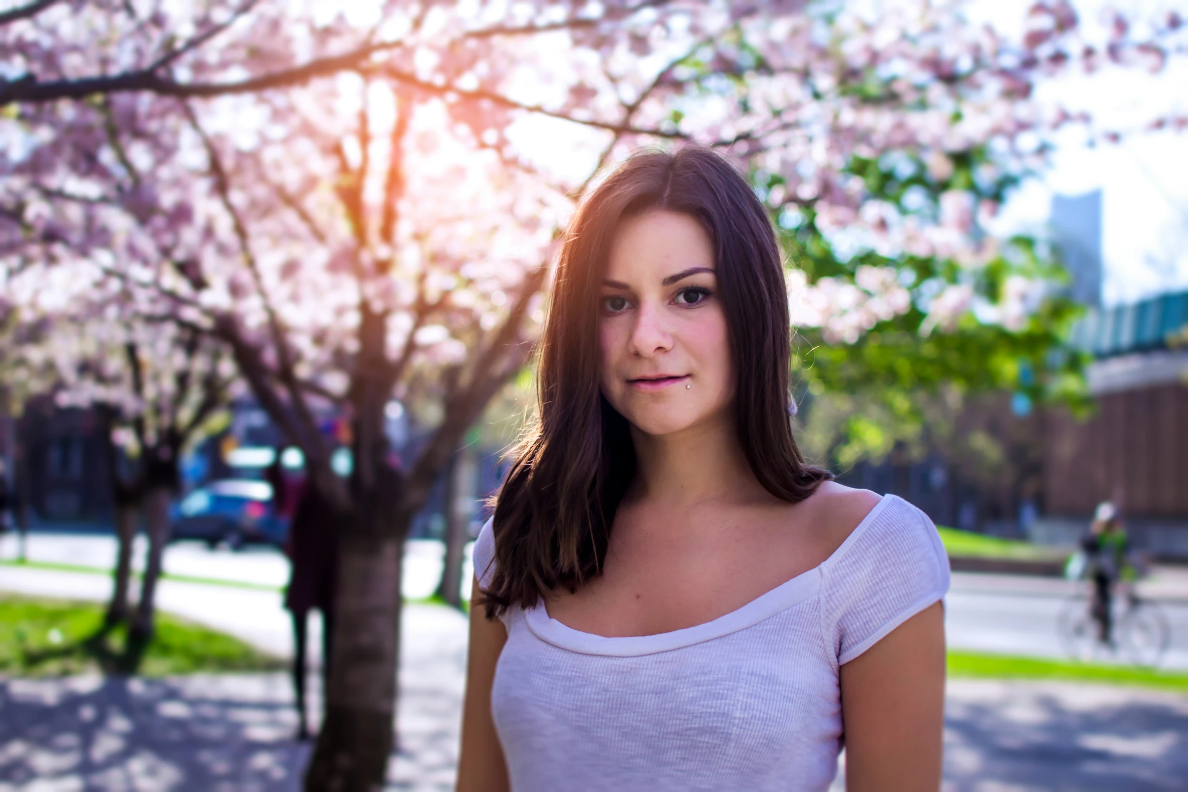 a young woman looking away in the sun behind a flowering tree