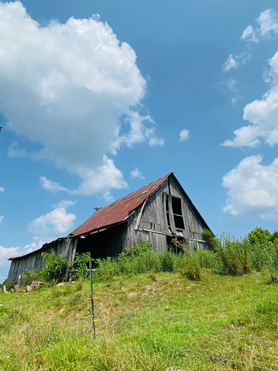 a barn in a grassy field under a cloudy sky