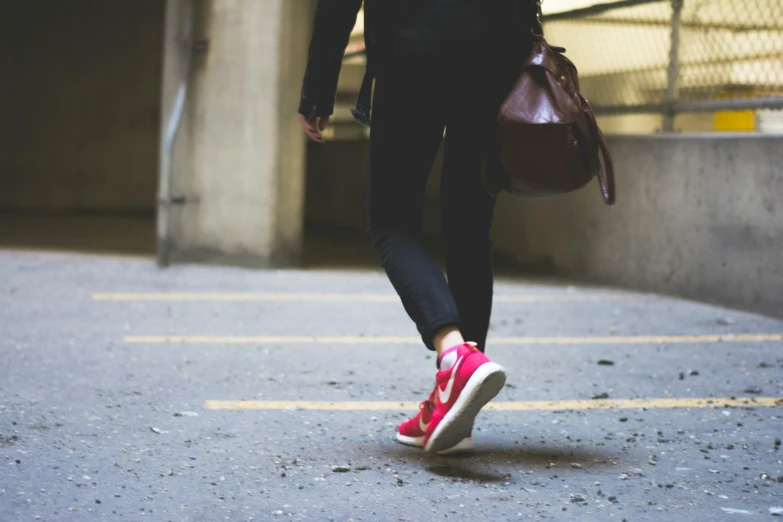 a person in pink tennis shoes and a brown bag