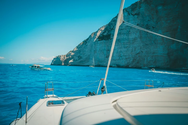 people on the deck of a boat approaching large cliffs