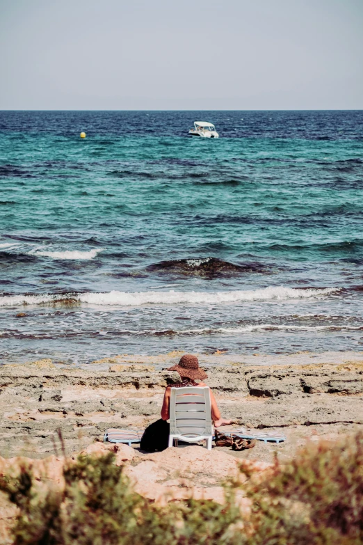 the woman is sitting on a chair on the beach