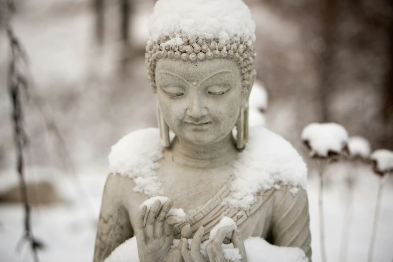 a statue of buddha praying in the snow